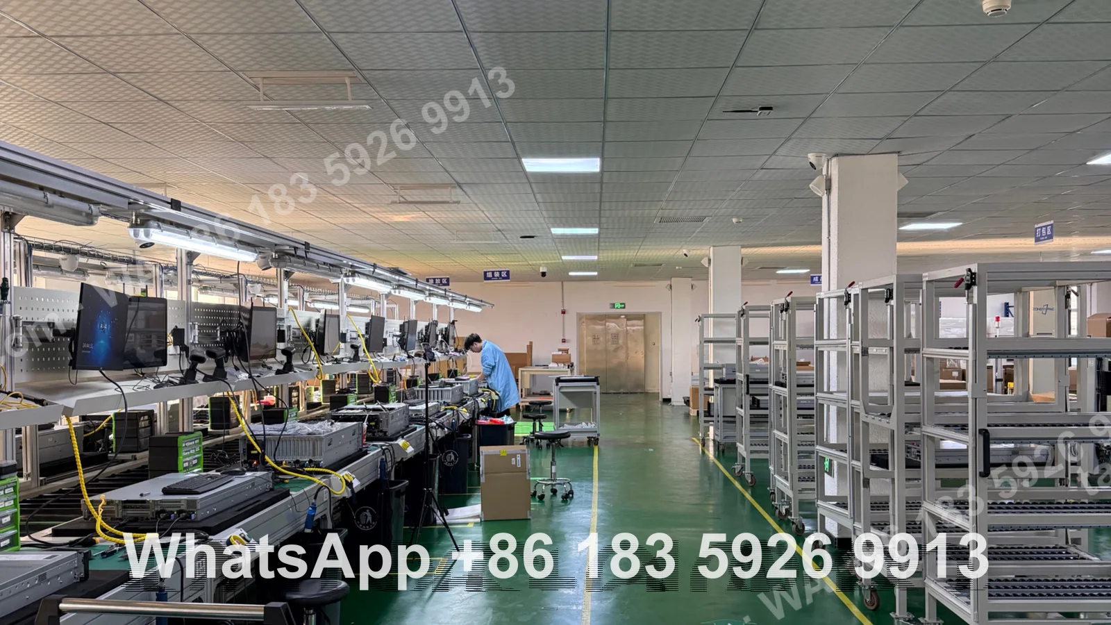 A long ESD workbench line with monitors and servers under test, a technician in an anti-static coat working at the far end
